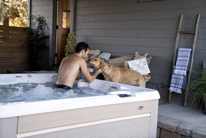 Man in backyard spa playing with dog